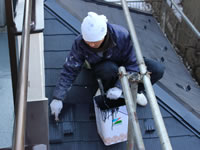 下屋根を上塗り塗装する職人